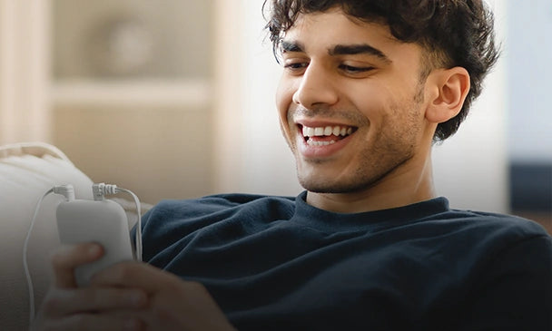 Adult using a KONGZEE portable TENS unit while relaxing at home