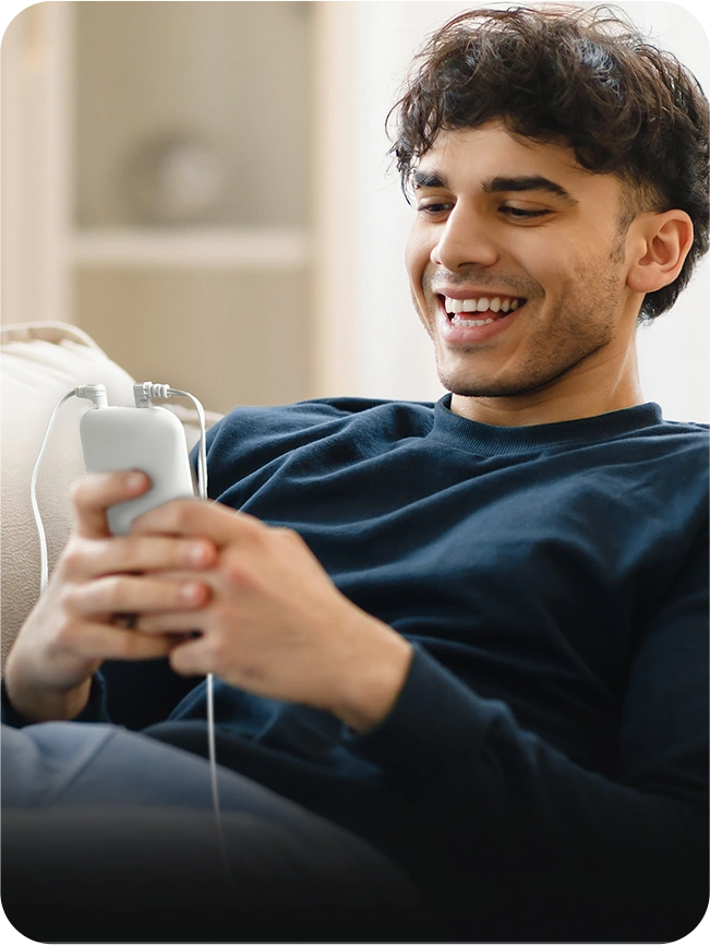 Adult using a KONGZEE portable TENS unit while relaxing at home
